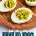 Deviled eggs topped with green filling and sprinkled with paprika on a wooden platter. Text overlay: "Easy Delicious Deviled Eggs Without Mayo.