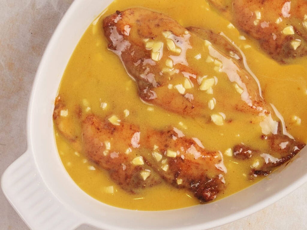 Stuffed squid in a light yellow sauce with garlic pieces, served in a white oval dish.