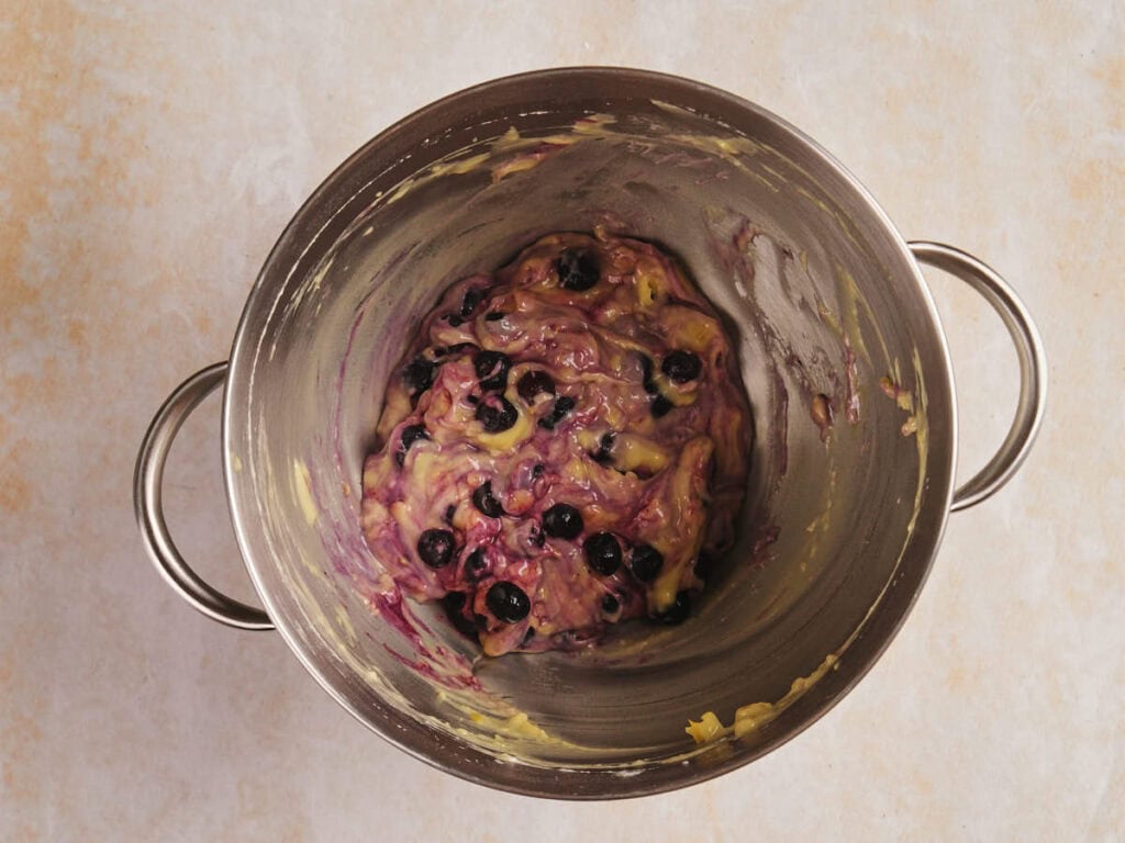Bowl containing a partially mixed batter with blueberries.