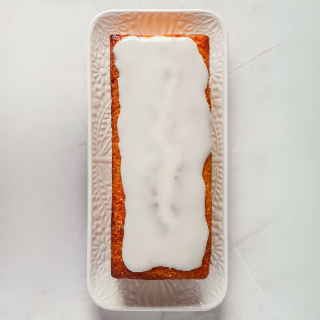 A rectangular cake with white icing sits on a decorative white platter.