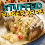 Close-up of a stuffed mushroom topped with melted cheesy filling, served on a plate, with text promoting creamy and cheesy air fryer stuffed mushrooms.