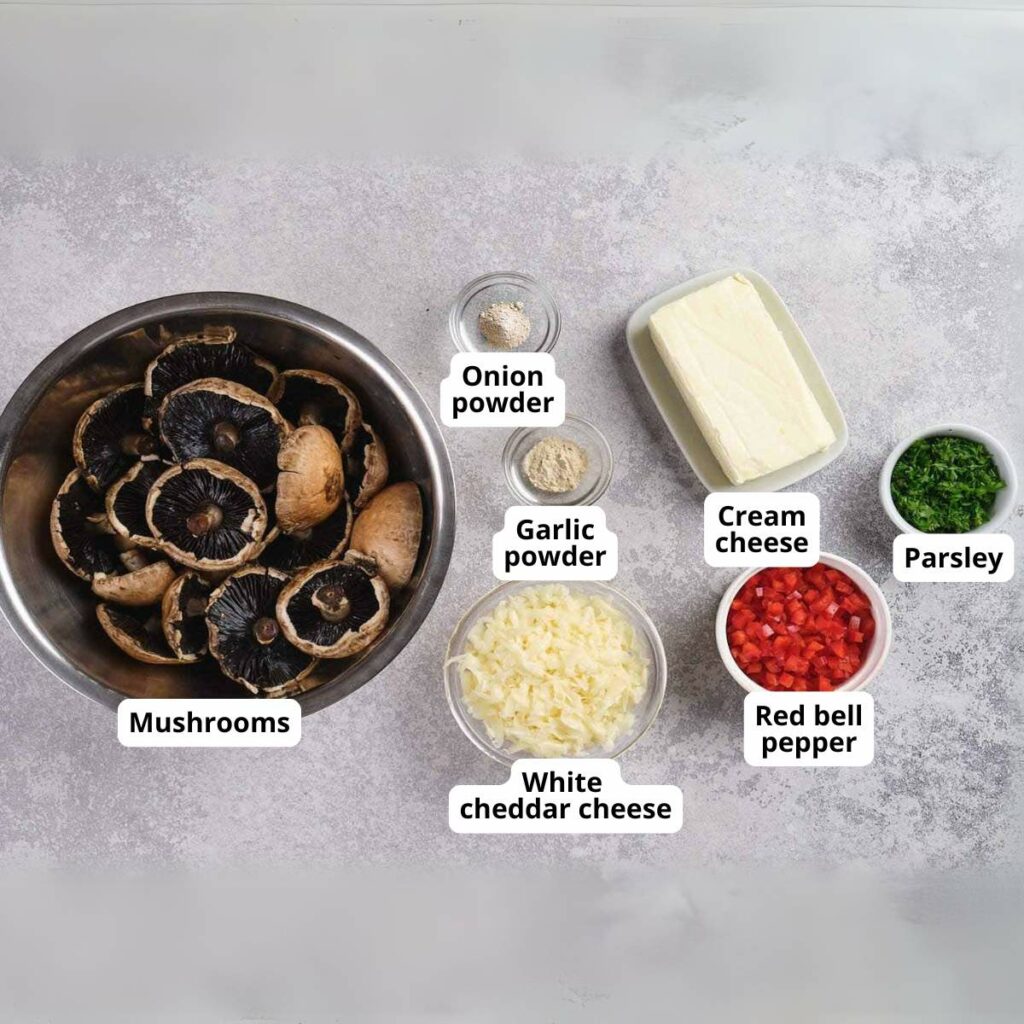 Labeled ingredients for stuffed mushroom on a grey colored surface.