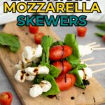 Skewers with cherry tomatoes, mozzarella balls, and basil leaves arranged on a wooden board, drizzled with balsamic glaze.