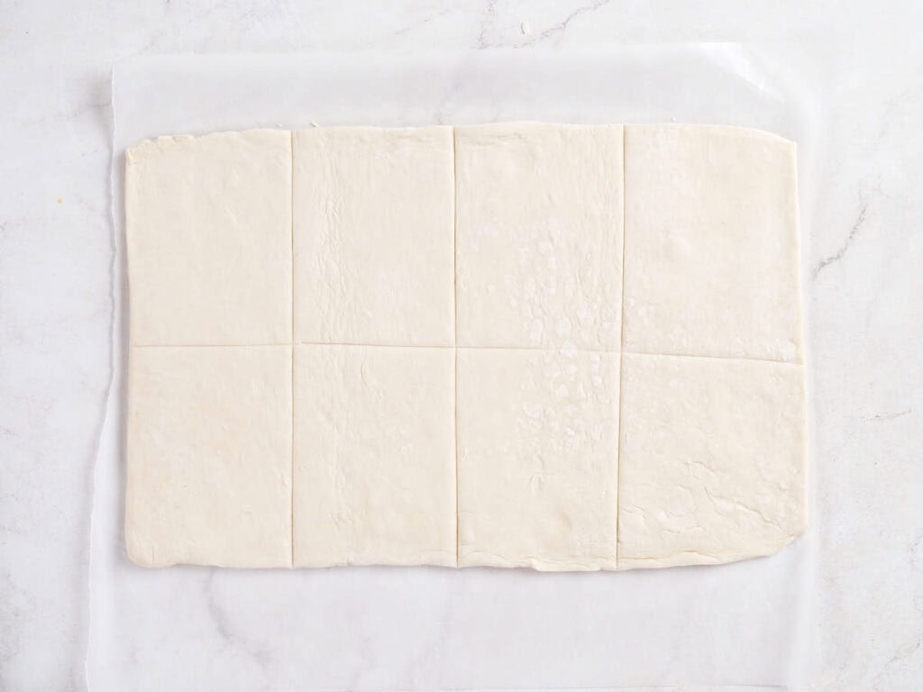 Rectangular sheet of puff pastry dough cut into eight even rectangles.