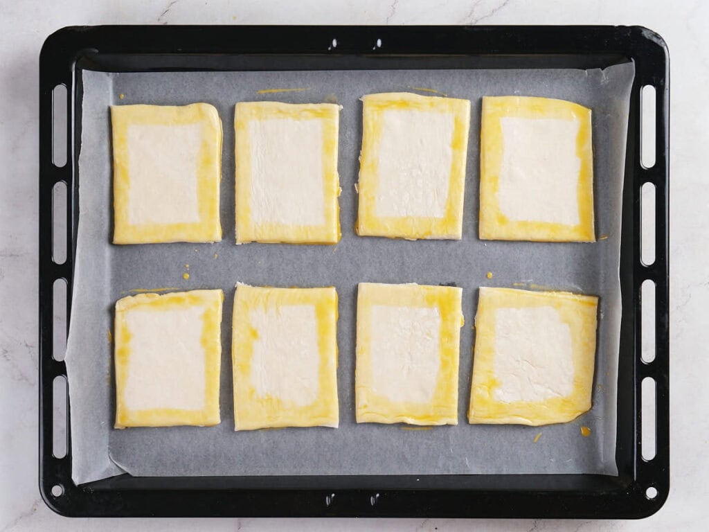 Eight rectangular pieces of puff pastry, brushed with egg wash along the edges.