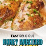 Two cooked chicken breasts in a honey mustard sauce, garnished with chopped parsley, in a white baking dish.