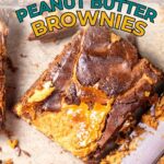 A close-up of a fudgy peanut butter brownie with a marbled chocolate and peanut butter top on a light surface, next to a partially visible knife.