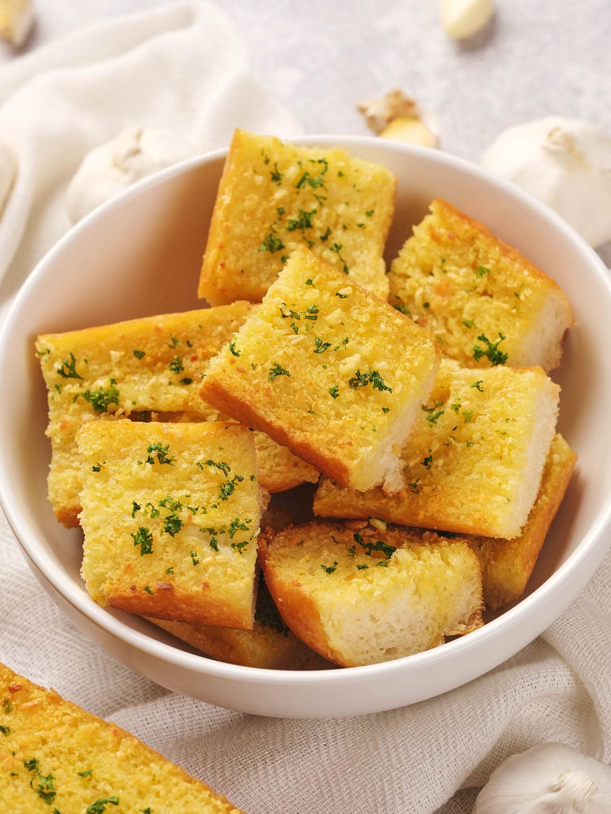 A bowl of roasted garlic bread cubes garnished with herbs.