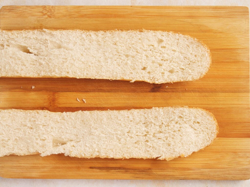 Two slices of bread are placed side by side on a wooden cutting board.