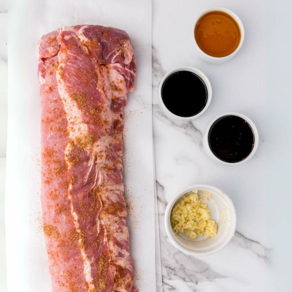 Raw pork ribs seasoned with dry rub on parchment paper.