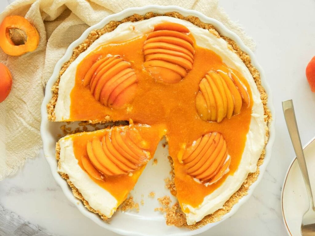 Apricot cheesecake with a creamy filling and sliced apricot halves on top.