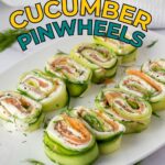 A white plate with salmon and cream cheese cucumber pinwheels, garnished with fresh dill, is displayed on a light surface. Text above reads "Salmon & Cream Cheese Cucumber Pinwheels.
