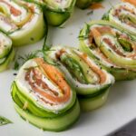 Rolled cucumber slices filled with cream cheese and smoked salmon, garnished with fresh dill.