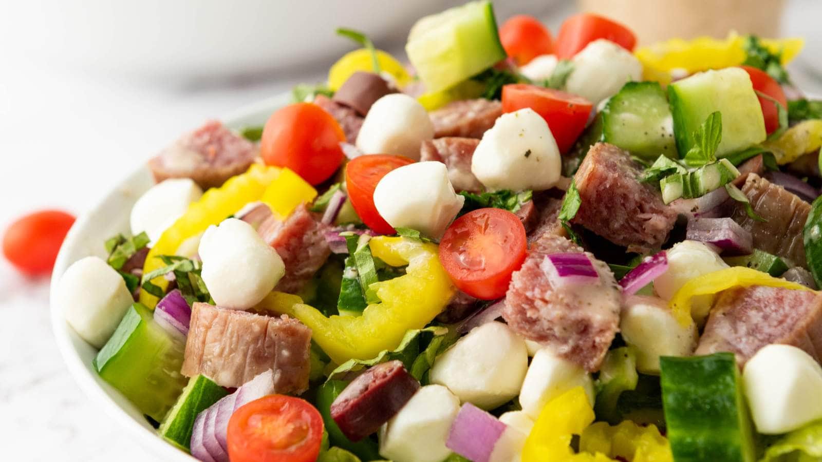 A close-up of italian chopped salad in a white bowl.