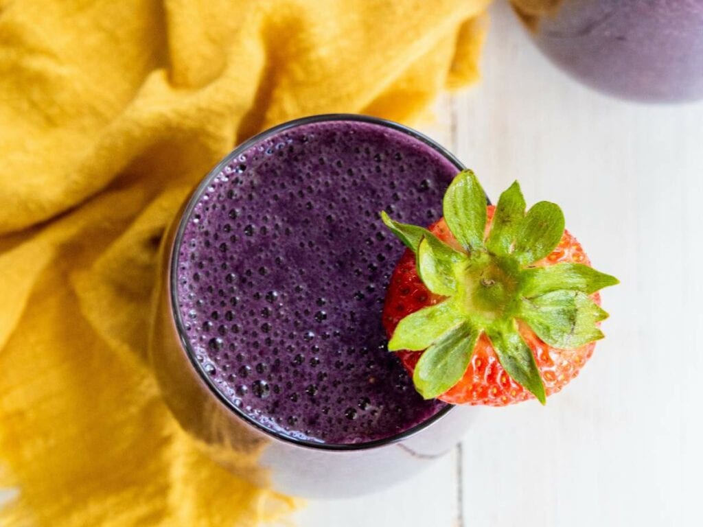 Mixed berry smoothie with a strawberry on top.