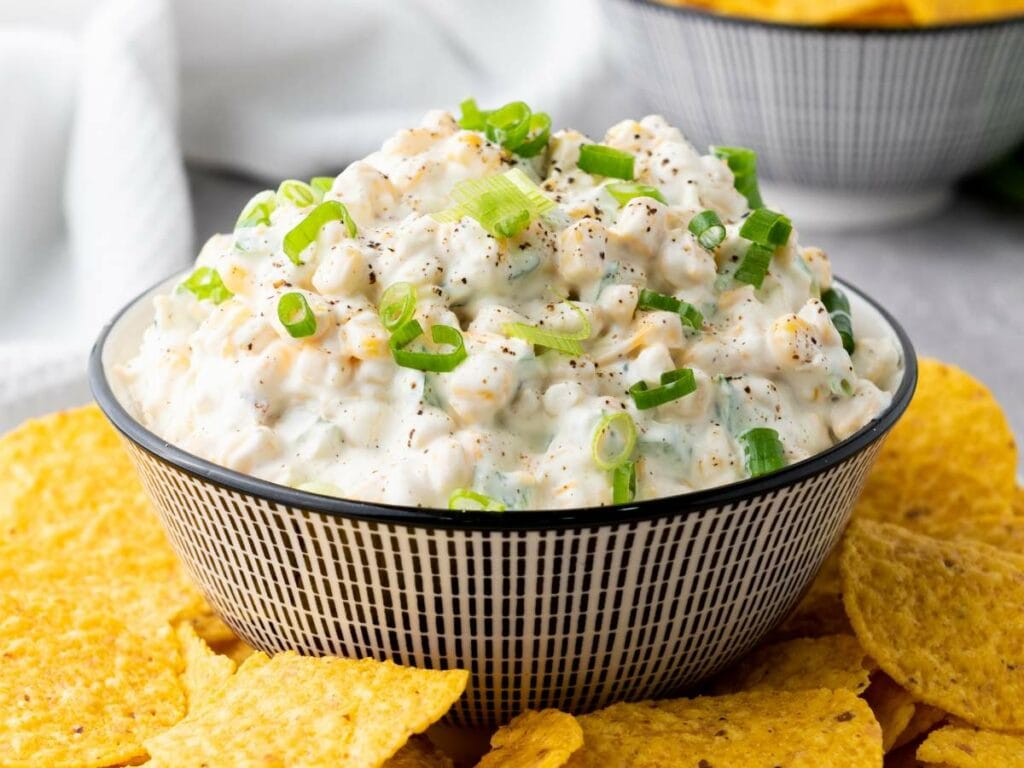 A bowl of creamy corn dip topped with chopped green onion.