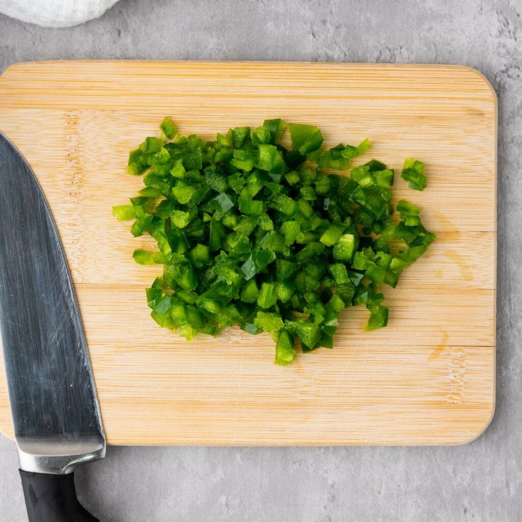Chopped green bell pepper on a wooden cutting board.