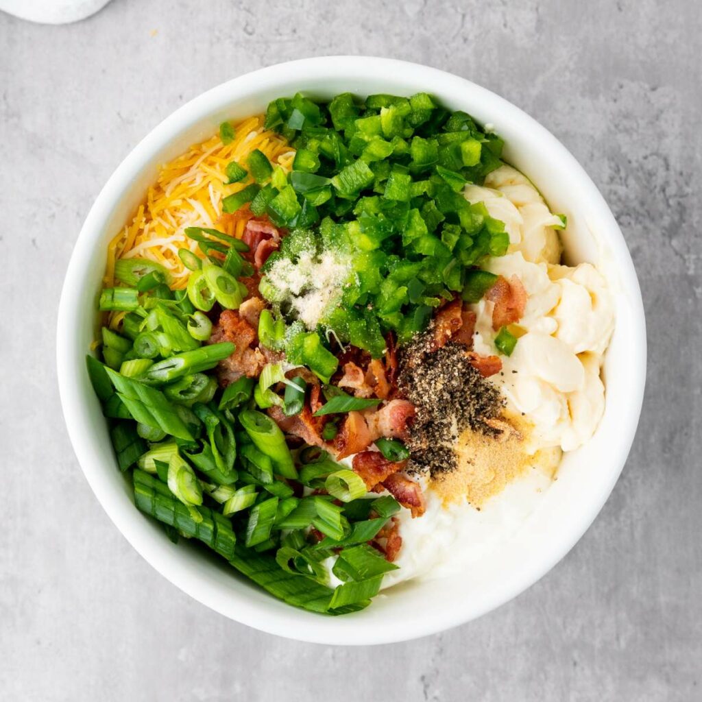 A white bowl containing creamy corn dip ingredients.