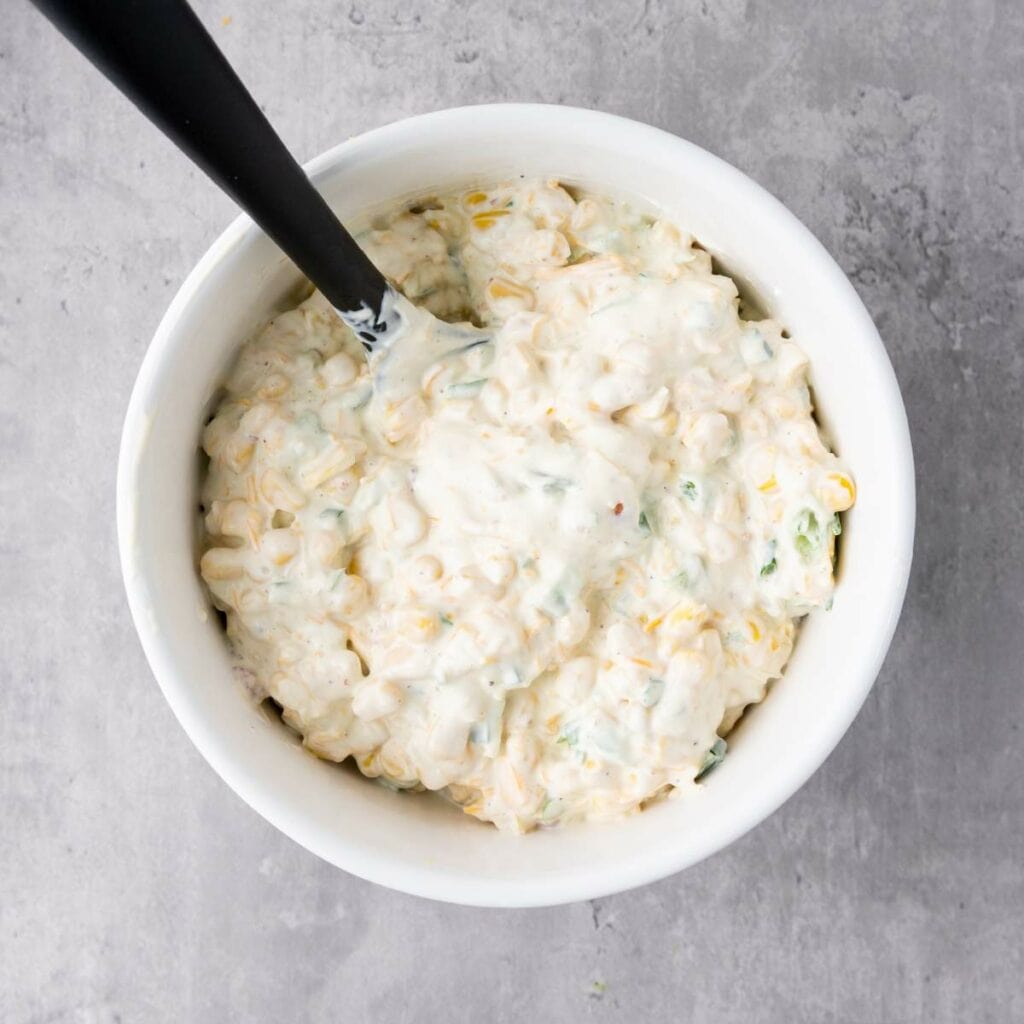 A white bowl filled with a creamy corn dip.