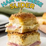 Two ham and cheese sliders with poppy seed topping are stacked on a white plate, secured with a toothpick. Text above reads, "Sweet & Savory Ham & Cheese Slider.