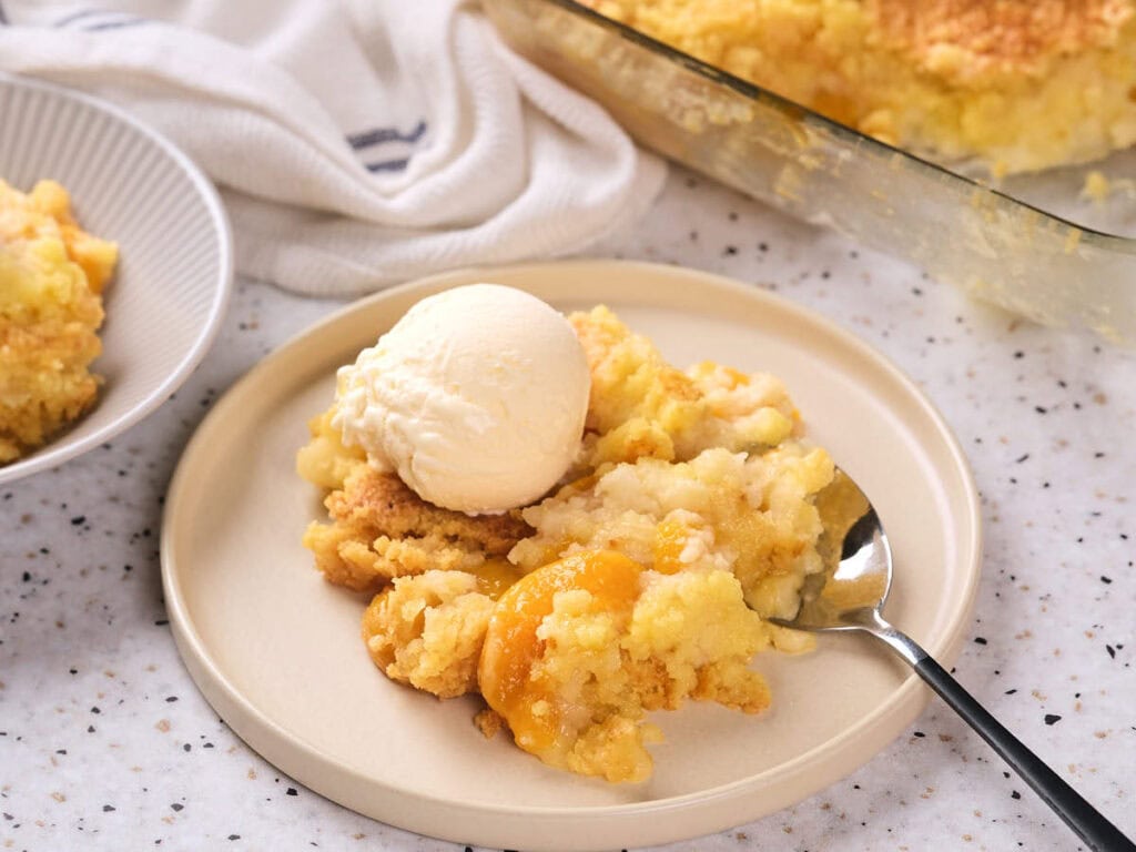 A serving of peach cobbler with a scoop of vanilla ice cream on a plate.