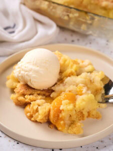 A serving of peach cobbler topped with a scoop of vanilla ice cream.