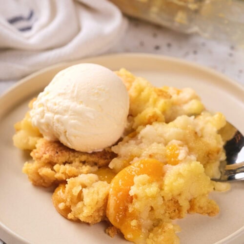 A serving of peach cobbler topped with a scoop of vanilla ice cream.