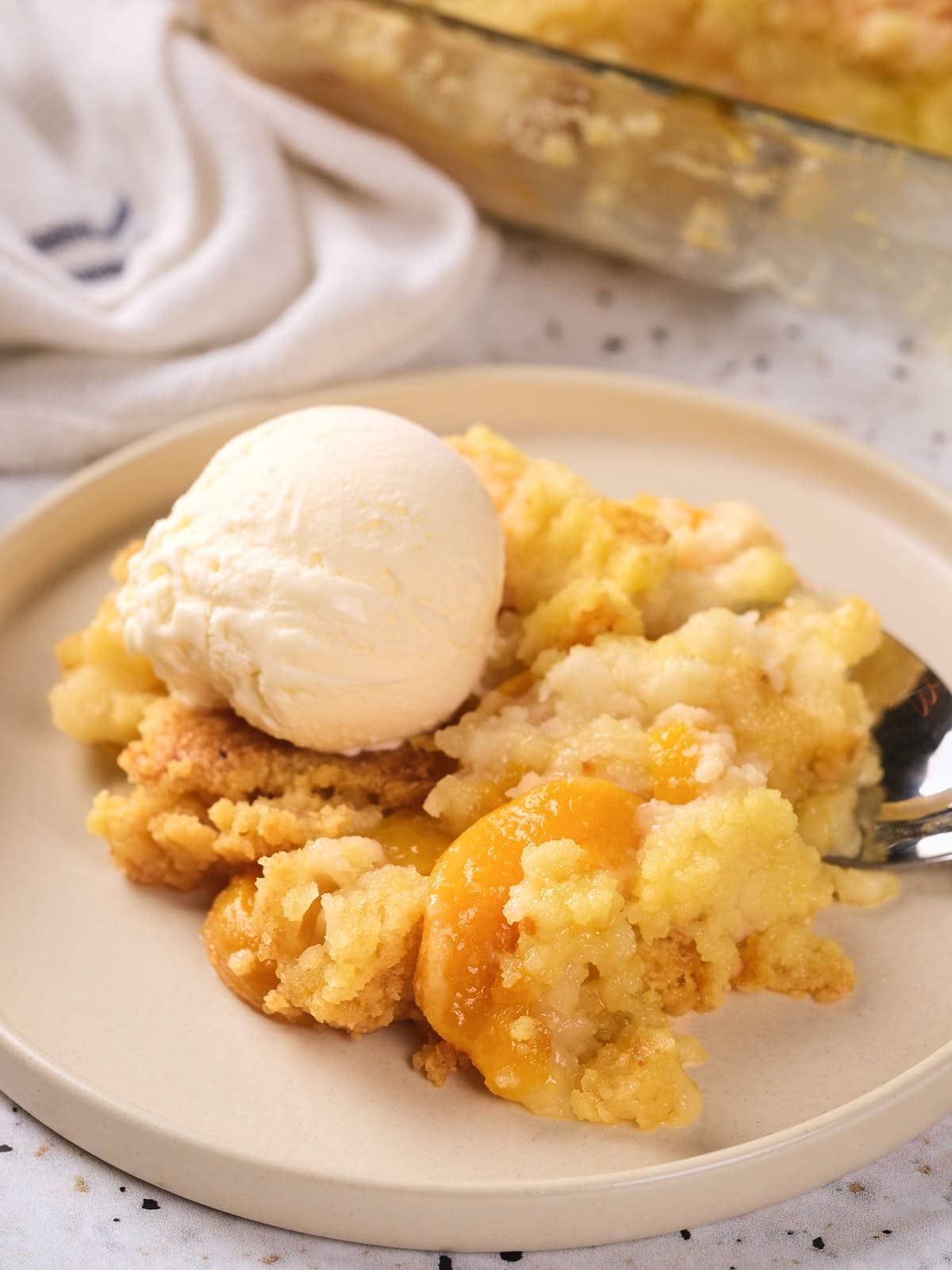 A serving of peach cobbler topped with a scoop of vanilla ice cream.