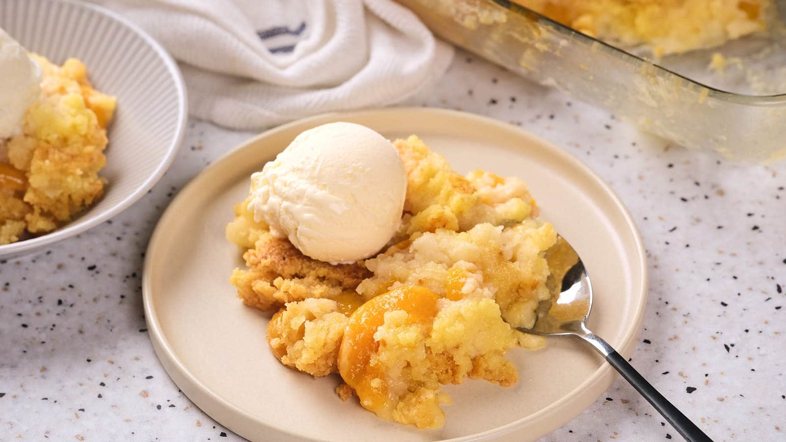 A plate of peach cobbler topped with a scoop of vanilla ice cream.