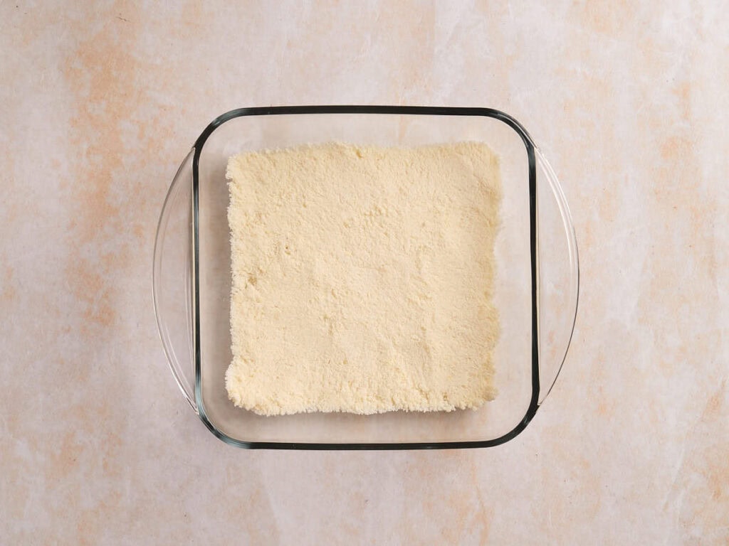 A glass baking dish filled with an even layer of pale yellow powder.