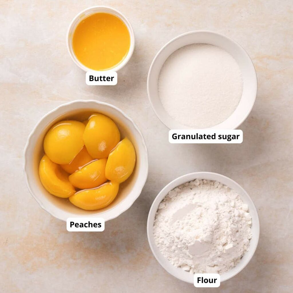 Four labeled bowls on a counter containing butter, granulated sugar, peaches, and flour.