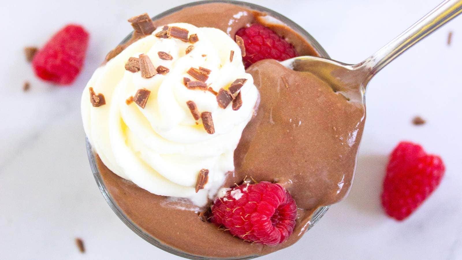 A glass cup filled with protein pudding topped with whipped cream.