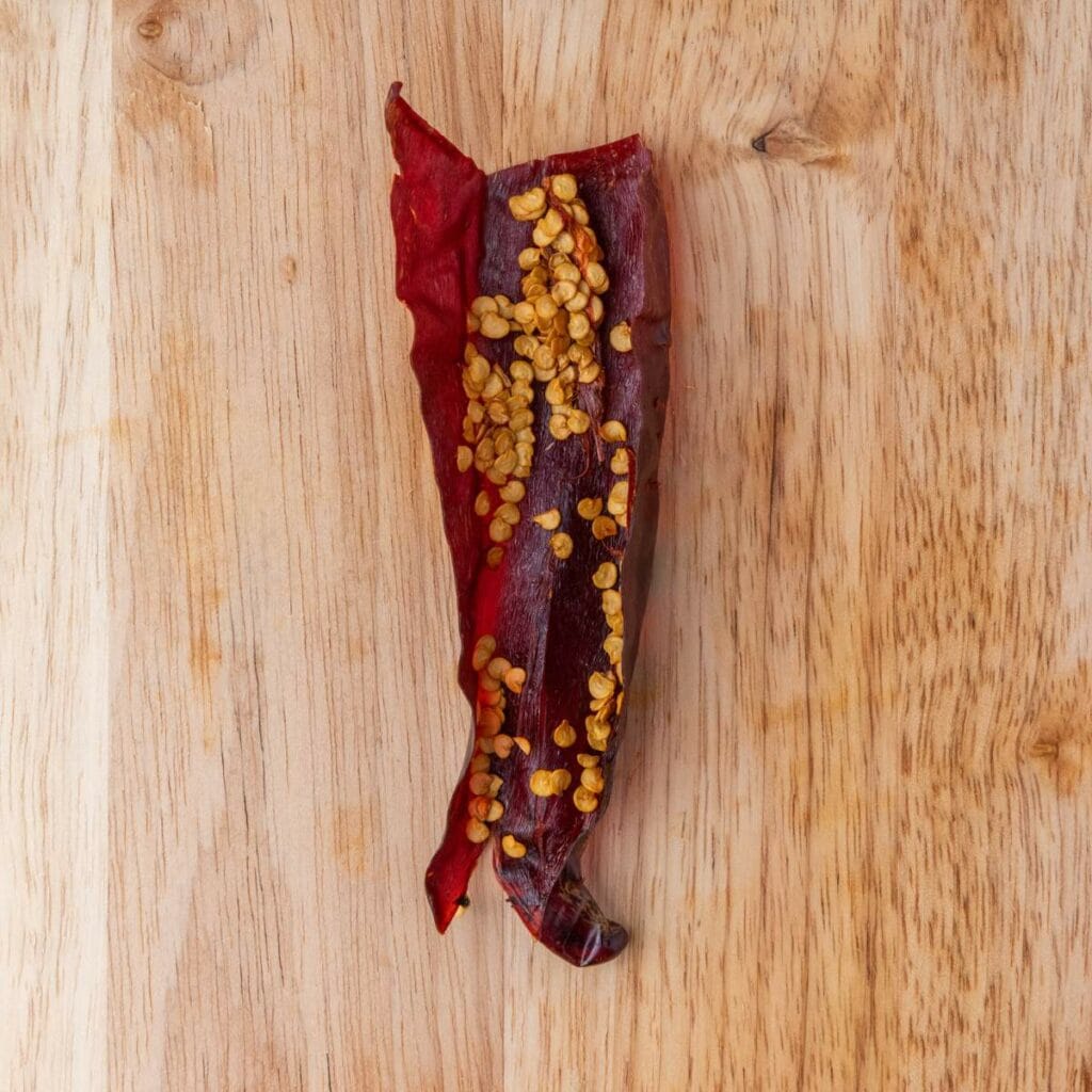 A dried red chili pepper with seeds.