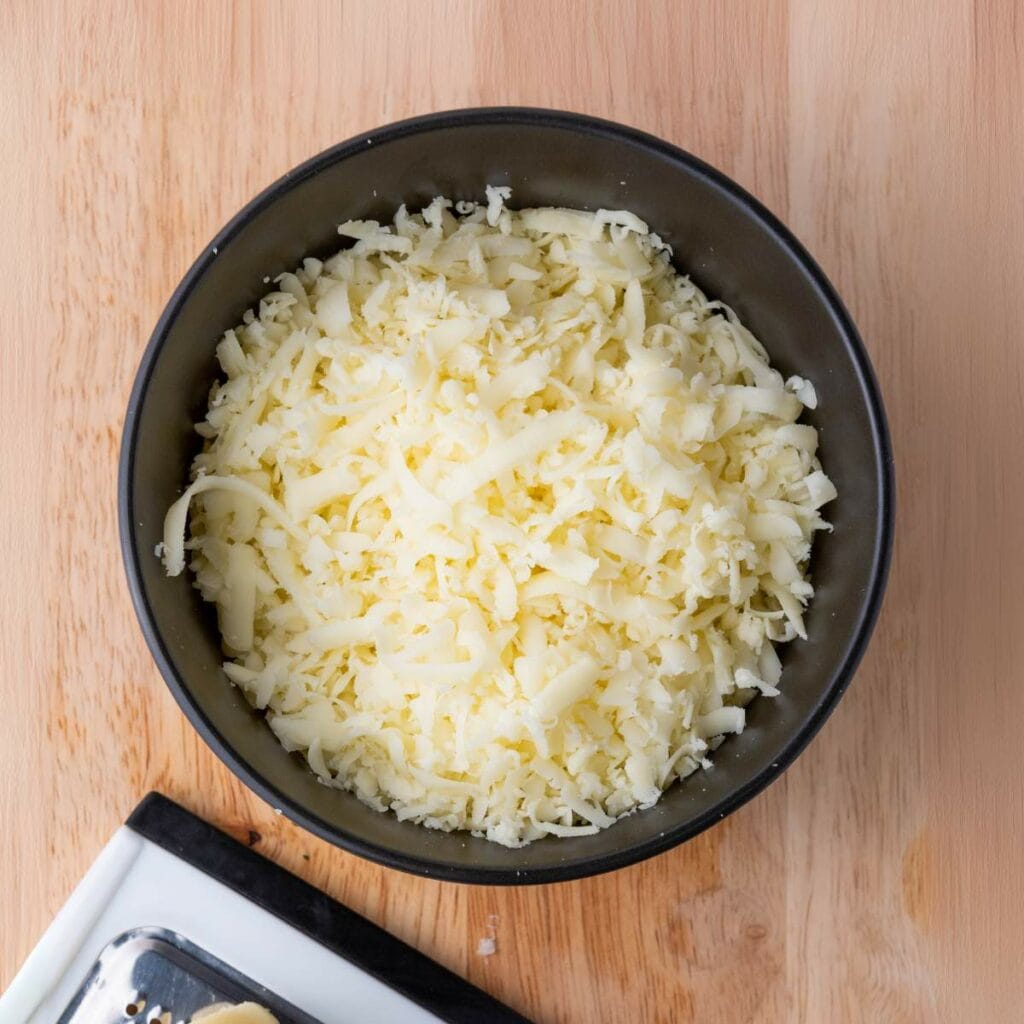 A black bowl filled with shredded white cheese.
