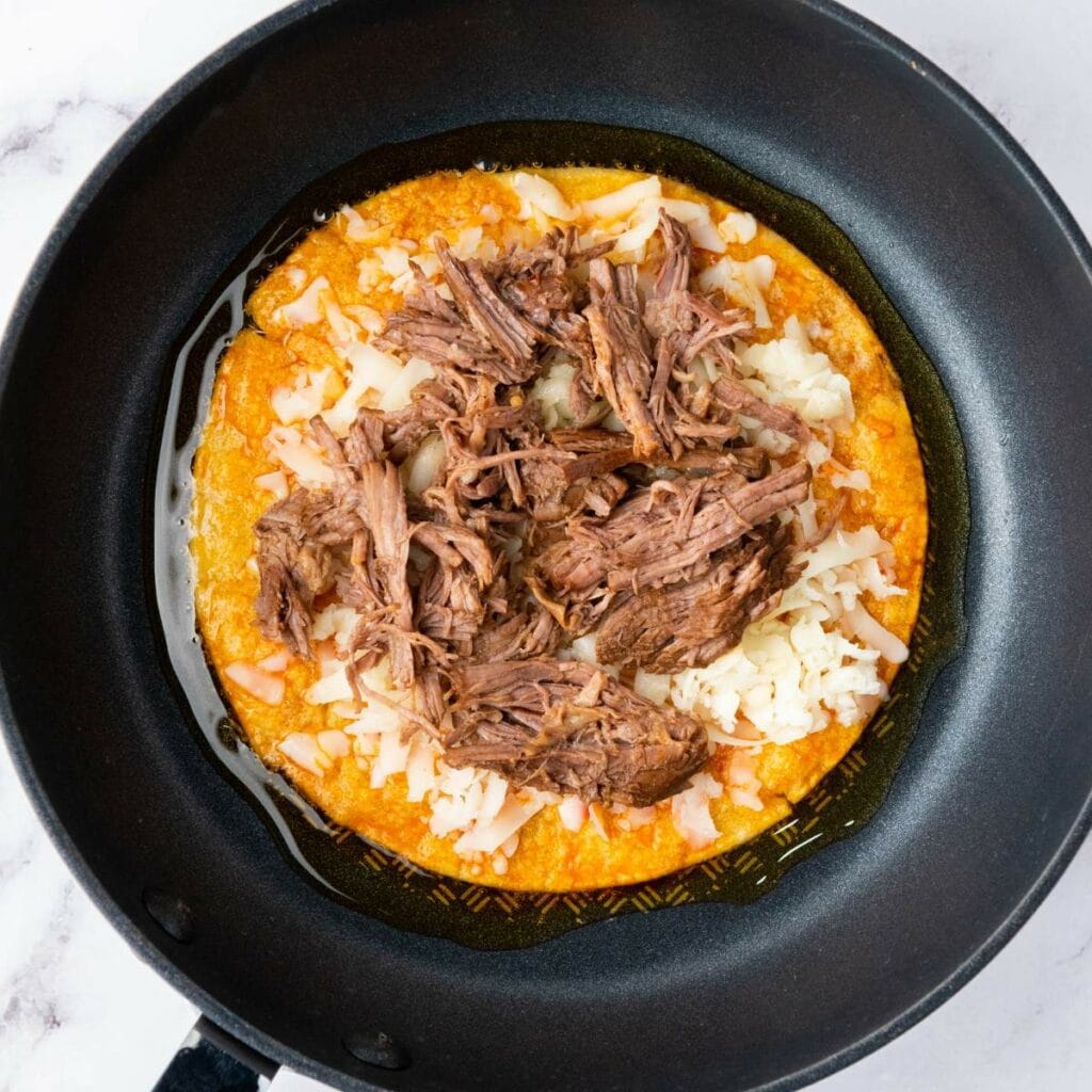 Shredded beef and melted cheese on a tortilla.