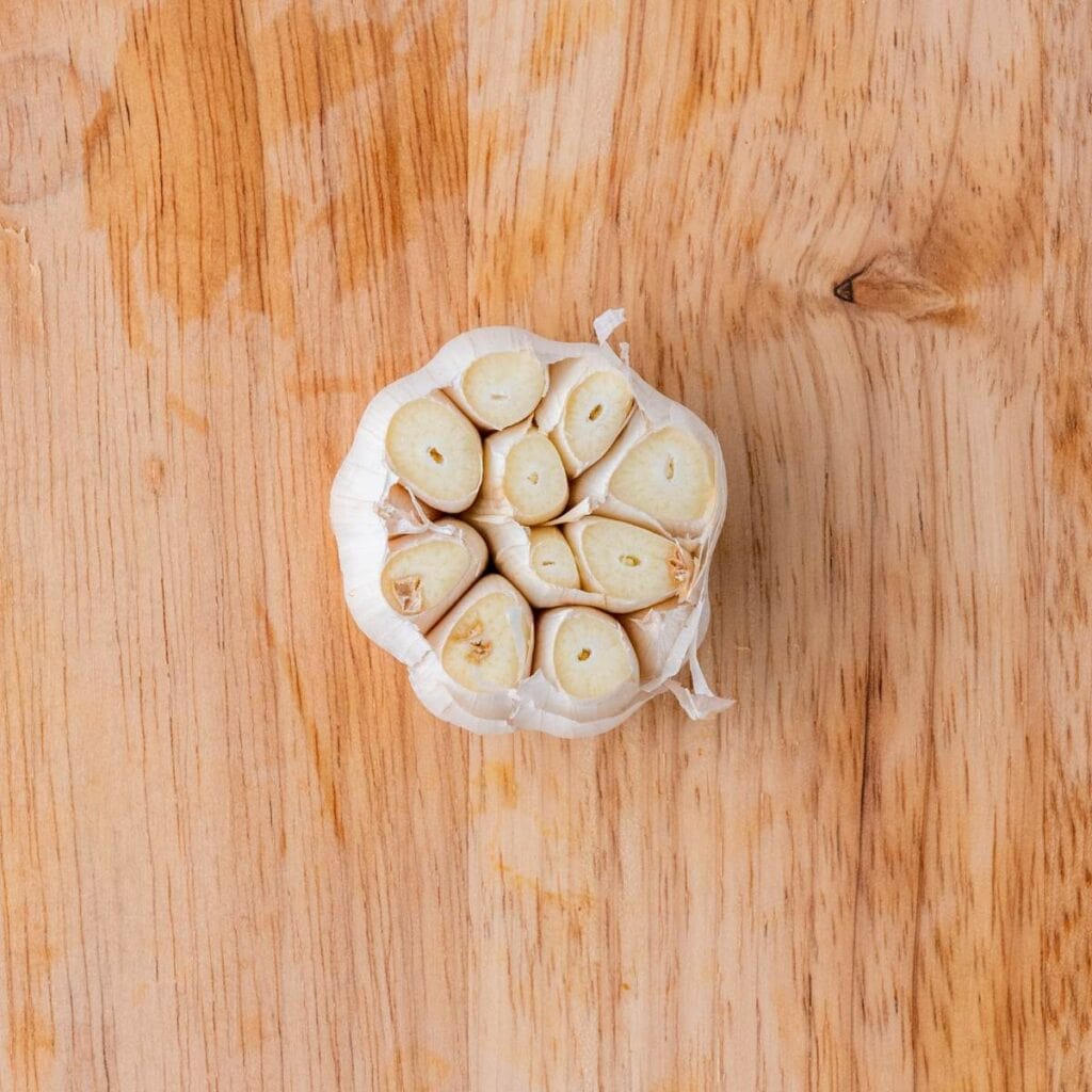 A head of garlic with the top sliced off.