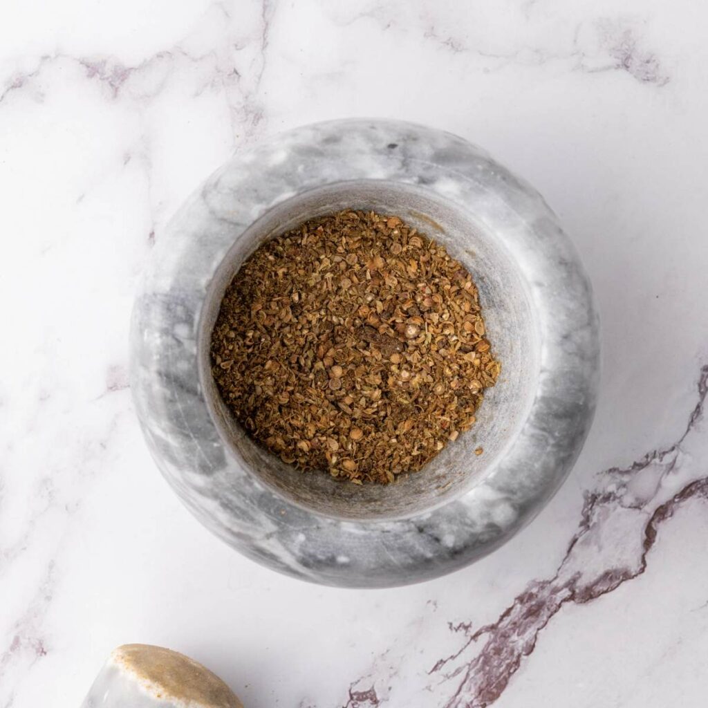 A marble mortar filled with ground spices or herbs.