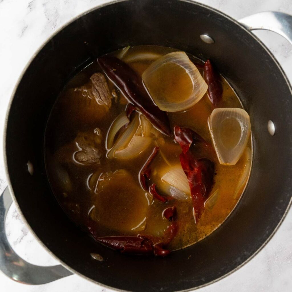 A pot containing broth and seasonings.
