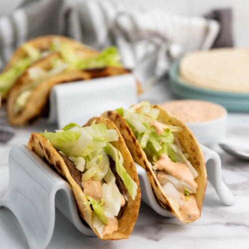 Three smash burger taco with shredded lettuce and sauce.