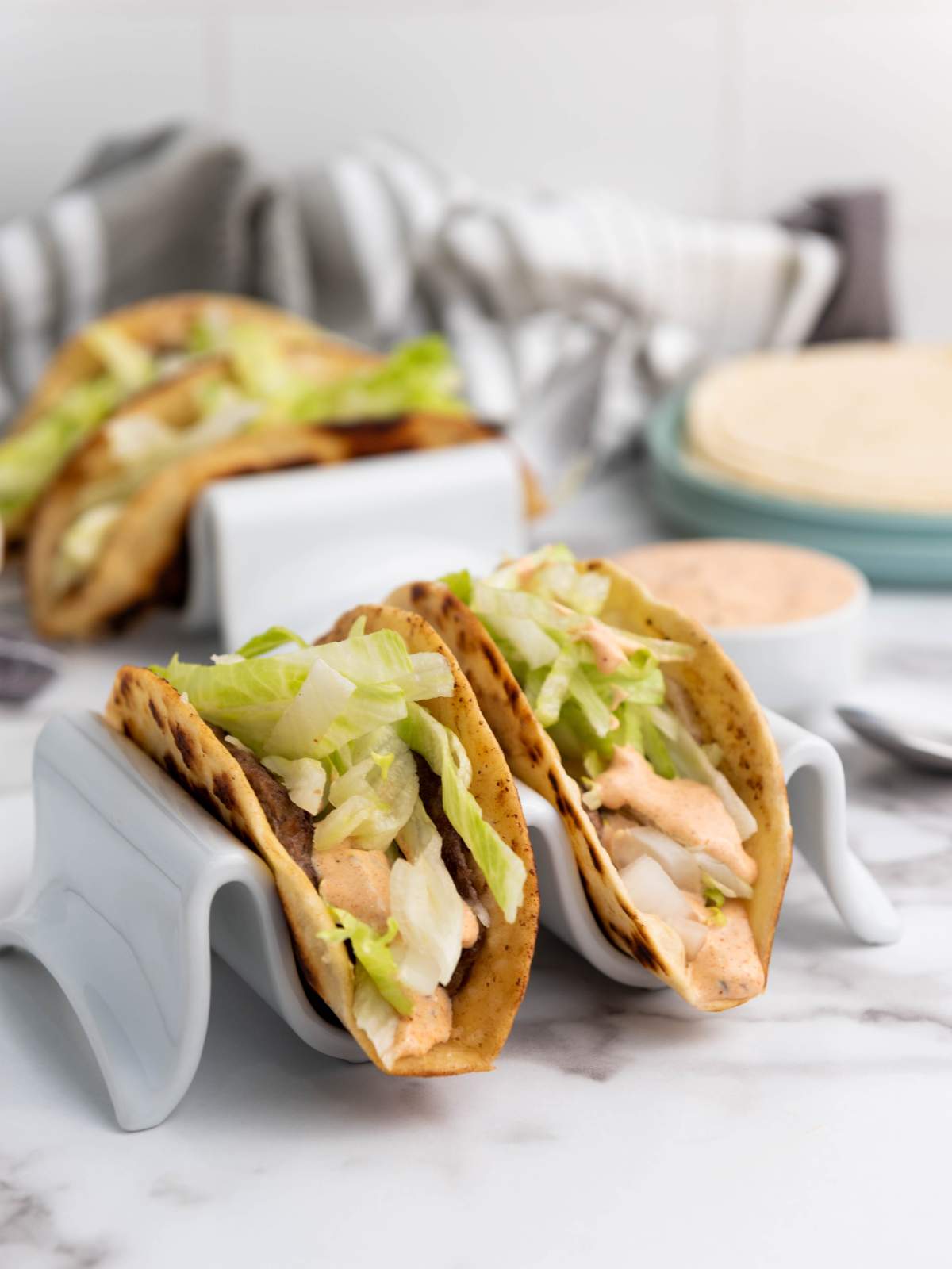 Three smash burger taco with shredded lettuce and sauce.