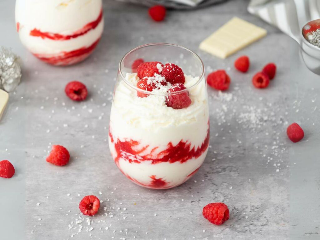 White chocolate mousse filled with layers of white cream and red raspberry sauce, topped with fresh raspberries and grated white chocolate.