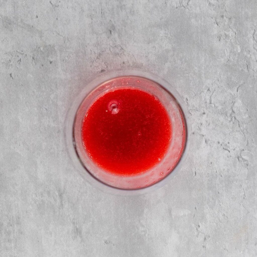 A glass filled with red liquid, viewed from above.
