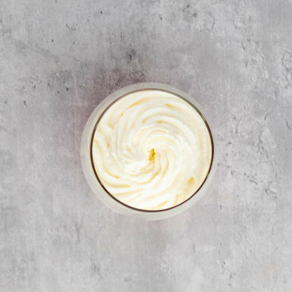 A glass bowl filled with swirled whipped cream.