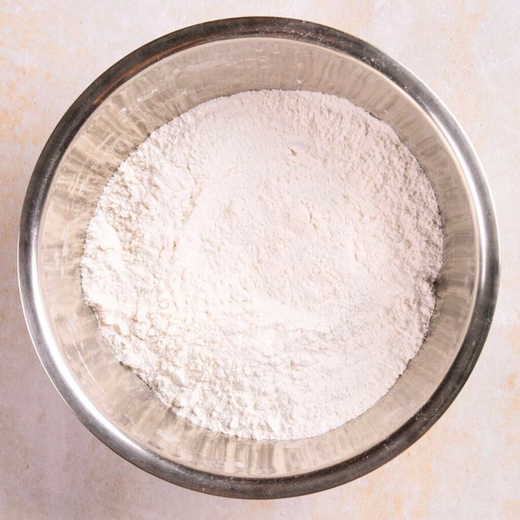 A stainless steel bowl filled with white flour.