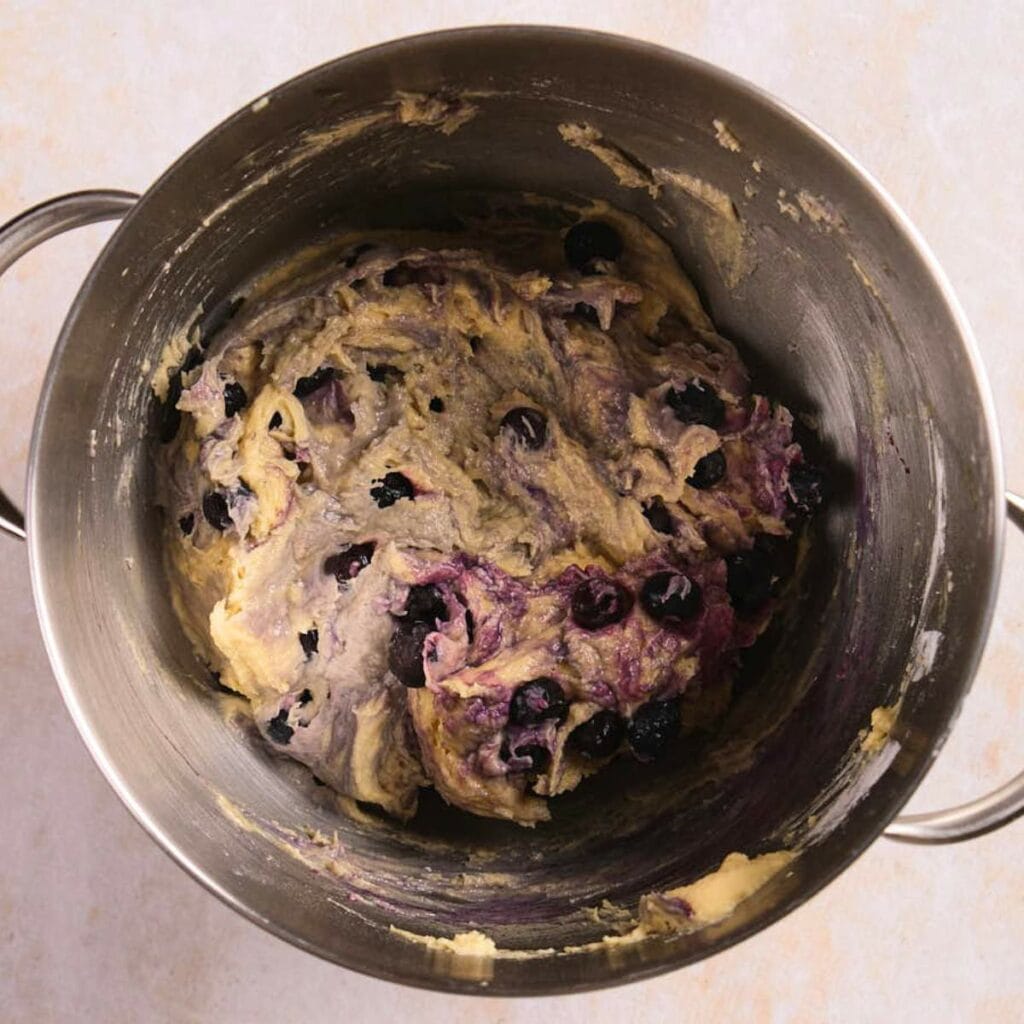 A mixing bowl containing thick batter with visible blueberries.