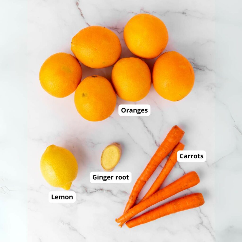 Top-view of carrot ginger juice labeled ingredients on a white marble surface.