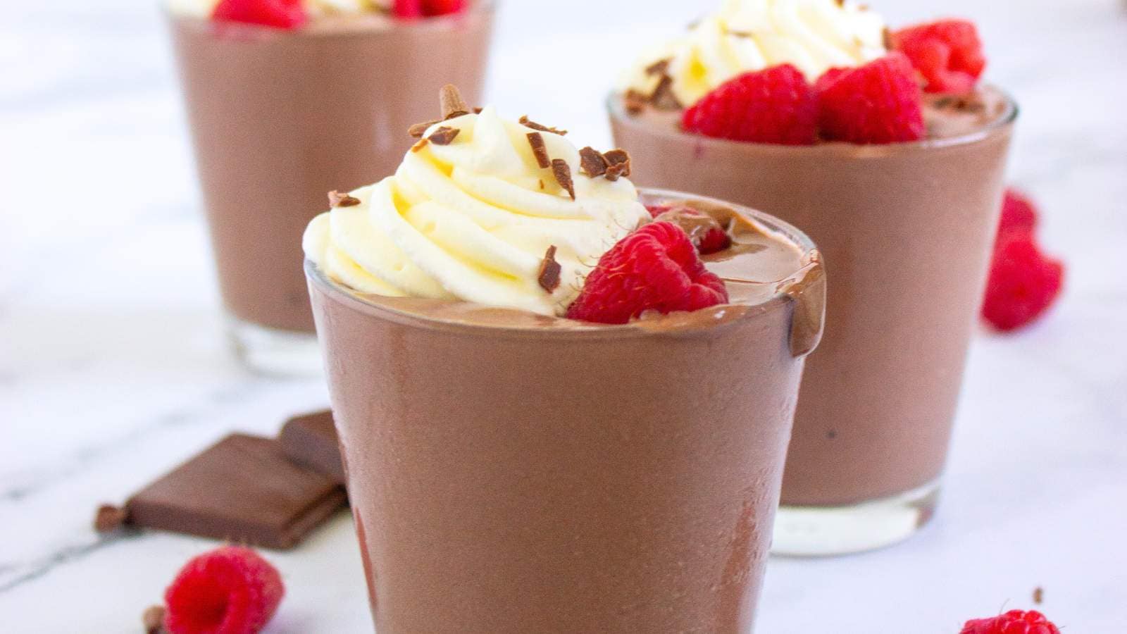 Chocolate cottage cheese pudding topped with whipped cream, chocolate shavings, and raspberries.