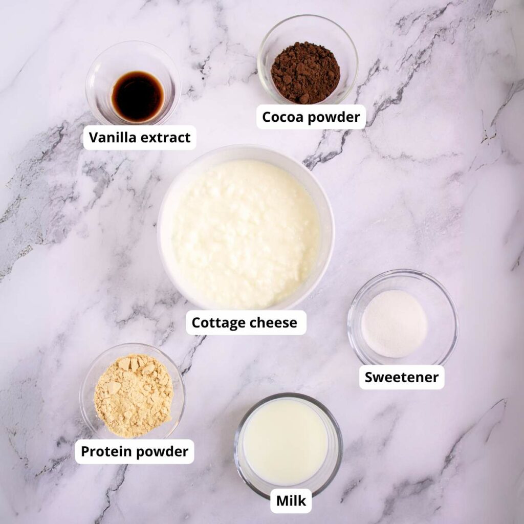 Top-down view of labeled ingredients in bowls of chocolate cottage cheese pudding in a light surface.