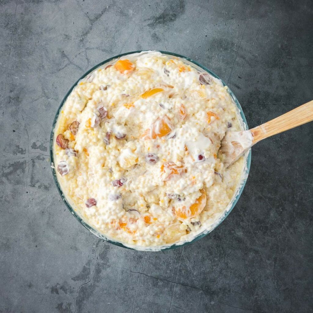 A glass bowl filled with a creamy mixture , with a wooden spoon resting inside.