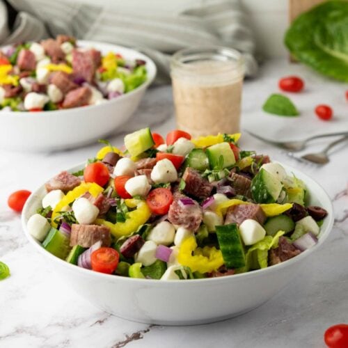 A bowl of italian salad with cucumbers and other ingredients.